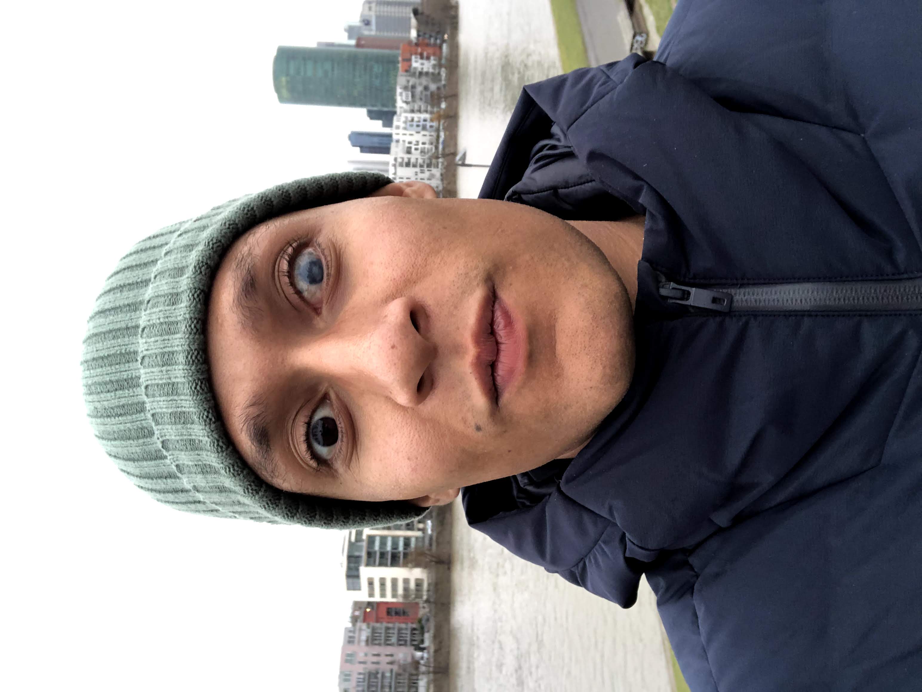 Ricky Rae draußen mit grüner Mütze und dunkelblauer Jacke